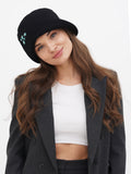 Woman in grey suit wearing black cloche hat, side view carrying black bag