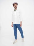 Full body side view of man in beige Gatsby newsboy cap with white shirt casual stance