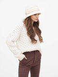 Woman standing with hand on hip wearing beige wool cloche hat