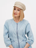 Woman in beige linen Breton cap with arms crossed, looking down