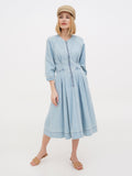 Woman in beige linen Breton cap and light blue dress standing full length