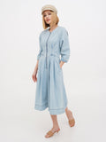Woman wearing beige linen Breton cap with light blue linen dress, walking