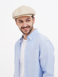 Man wearing beige linen newsboy cap front view smiling