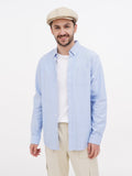 Man in beige linen newsboy cap full body light blue shirt