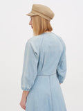 Woman wearing beige linen newsboy cap and blue dress, full length side view