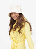 Woman wearing beige wool cloche hat with side bow, yellow dress