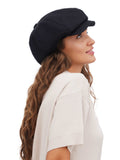 Side profile of woman in black cotton baker boy cap with long curly hair