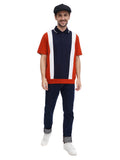 Full body shot man wearing black 8-panel newsboy cap with navy orange polo and dark pants