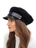 Woman holding black cashmere Breton cap showing lacquered rim and crown structure