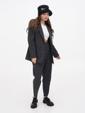 Woman in tailored grey suit wearing black cloche hat, three-quarter standing pose