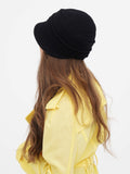 Side profile of black wool cloche hat with yellow coat collar
