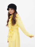 Woman in black cloche hat and yellow coat, walking, side view
