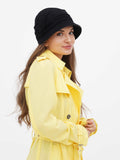Woman wearing black cloche hat and yellow coat, three-quarter view