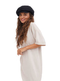 Three-quarter view of woman in black cotton baker boy cap with white dress