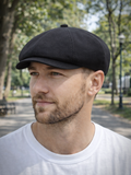 Man wearing black linen newsboy cap front view summer outdoors