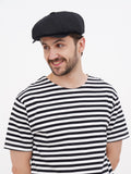 Man in black linen newsboy cap striped tee portrait