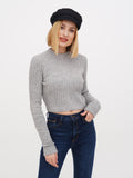 Close-up of woman in black linen newsboy cap with grey sweater, hands together