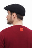 Back view man in black 8-panel newsboy cap showing construction with burgundy sweater