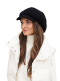 Full body view of woman in black wool baker boy cap with white winter coat