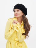 Close-up of black wool beret on woman's head showing flower embellishment detail and adjustable fit