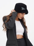 Woman adjusting black wool cloche hat with rhinestone trim, wearing charcoal blazer