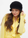 Woman wearing black wool cloche hat with pin-tucked seams, yellow trench coat