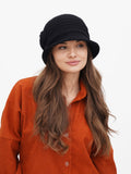 Woman wearing black wool cloche hat with upturned brim, paired with rust orange shirt