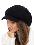 Woman adjusting brim of black wool newsboy cap portrait view