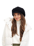 Woman in white winter coat wearing black wool newsboy cap close-up portrait