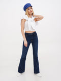 Side view of woman in blue linen Breton cap, white top and dark flared jeans