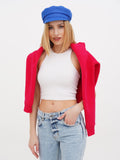 Woman wearing blue linen Breton cap and red cardigan looking to the side