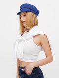 Close-up angle of woman wearing blue linen Breton cap with white crop top