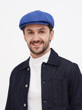 Man wearing blue linen newsboy cap front view with black denim jacket