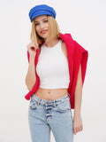 Woman in blue linen newsboy cap with red cardigan, white top and jeans
