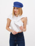 Cropped close-up of woman in blue linen newsboy cap with white top