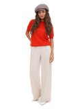 Full body view of woman in cappuccino brown baker boy cap with white trousers and red top