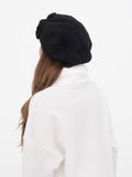Close-up of charcoal beret hat on woman's head showing dark grey flower embellishment detail