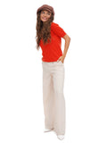 Full body view of woman in cocoa brown baker boy cap with red top and cream trousers