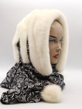 Cream white mink fur hat hood cowl with black patterned knit lining and pompons on mannequin, front three-quarter view