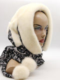 Detail view cream mink pompons at ends of black patterned fabric ties on mink fur hat hood