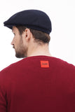 Smiling man wearing dark blue flat cap close-up portrait with burgundy sweater