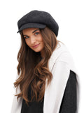 Smiling woman portrait wearing dark grey cashmere baker boy hat white background