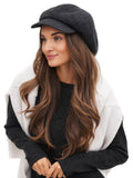 Woman in black and white colour-block jacket wearing dark grey cashmere newsboy cap portrait