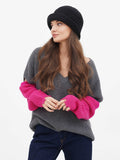 Woman with hand near chin wearing dark grey wool cloche hat, close-up front view