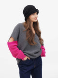 Woman with hands in pockets wearing dark grey cloche hat, three-quarter view