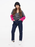 Full-length photo of woman wearing dark grey cloche hat, grey sweater and navy trousers