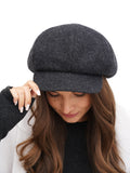 Three-quarter face view woman in dark grey cashmere paperboy cap