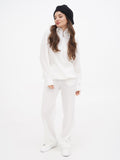 Dark grey wool beret hat on woman in white outfit, full length front view showing beret silhouette
