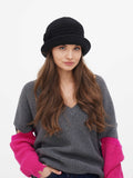 Woman wearing dark grey wool cloche hat with small fabric flower detail, pink knit sleeves