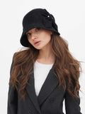 Woman wearing dark grey wool cloche hat with side bow detail, dark blazer